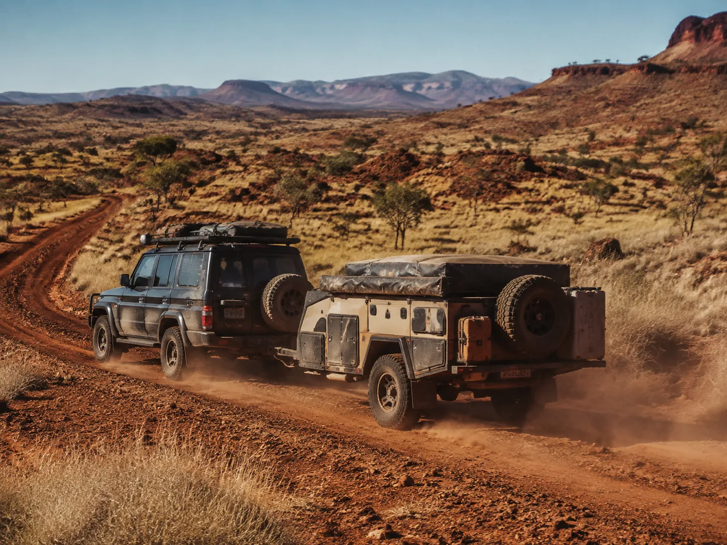 Four-wheel drive towing a camper trailer on a red dirt track