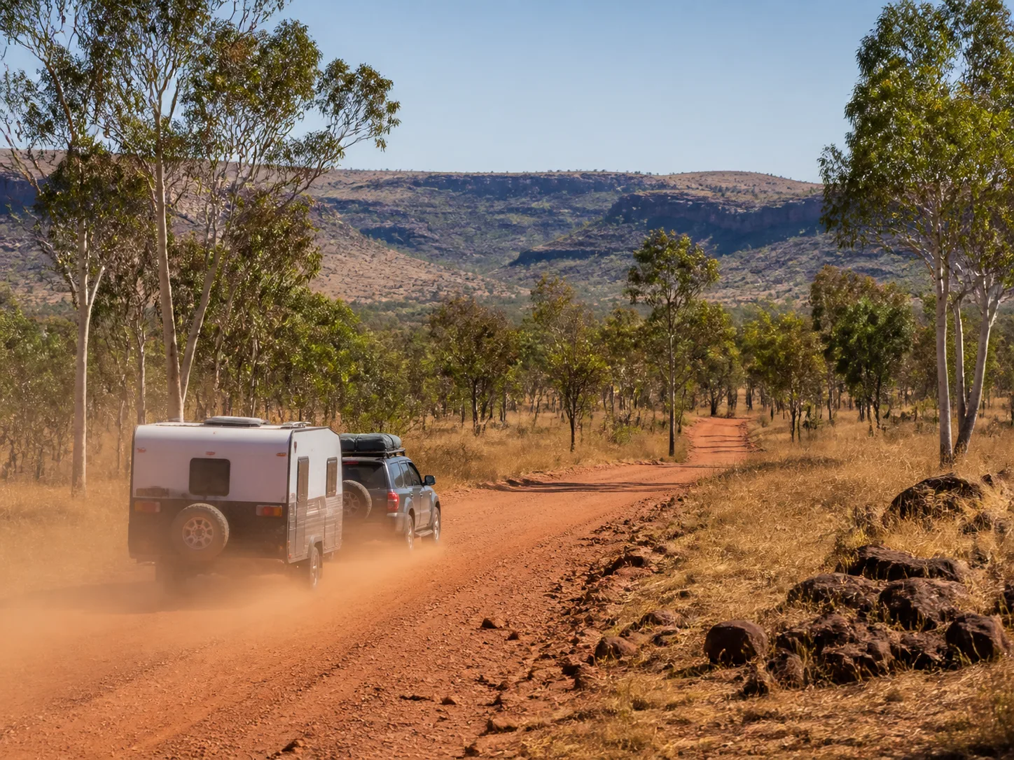 Four-wheel drive towing a caravan along the red dirt Savannah Way